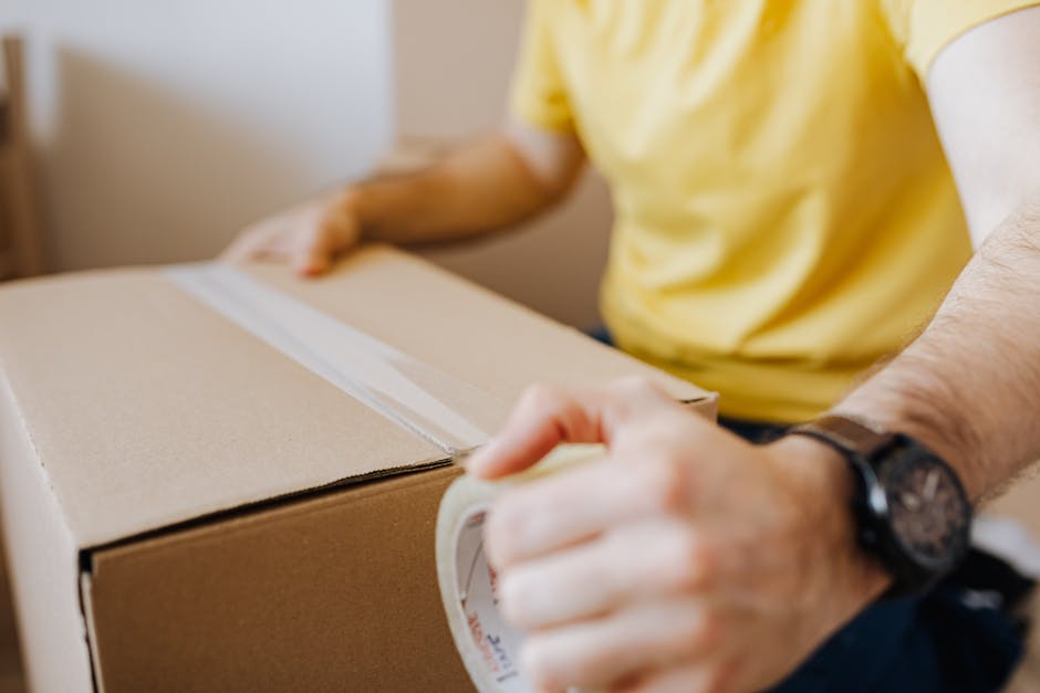 Movers taping a cardboard moving box securely